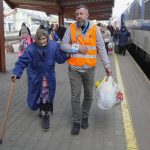 
              A volunteer helps an elderly Ukrainian refugee walk along a platform at a railway station in Przemysl, Poland, on Friday, March 25, 2022. (AP Photo/Sergei Grits)
            