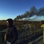 
              A Ukrainian soldier watches as smoke raises after an explosion near the airport, in Lviv, western Ukraine, Friday, March 18, 2022. The mayor of Lviv says missiles struck near the city's airport early Friday. (Ismail Coşkun/IHA via AP)
            