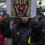 
              A woman holds a poster depicting Vladimir Putin, the Russian president, smeared in red paint, during a protest against the Russian military invasion of Ukraine, in Belgrade, Serbia, Sunday, March 6, 2022. A group of Russian citizens living in Serbia were among dozens of people on Sunday who braved freezing weather and a late winter blizzard to gather in central Belgrade in support of Ukraine and against the war that in the past 11 days has claimed scores of lives and driven 1.5 million people from their homes. (AP Photo/Marko Drobnjakovic)
            
