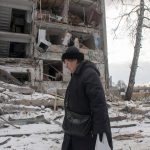 
              A woman walks past building damaged by shelling, in Kharkiv, Ukraine, Sunday, March 13, 2022. (AP Photo/Andrew Marienko)
            