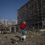 
              Irina Zubchenko walks with her dog Max amid the destruction caused after shelling of a shopping center, in Kyiv, Ukraine, Monday, March 21, 2022. (AP Photo/ (AP Photo/Rodrigo Abd)
            