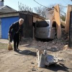 
              A woman sweeps in front of her house, fragments of a Russian rocket in the foreground, following a Russian attack in Kharkiv, Ukraine, Friday, March 25, 2022. (AP Photo/Efrem Lukatsky)
            