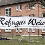 
              A banner reading "Refugees Welcome" hangs in front of a container village at the Bad Segeberg state shelter for refugees, Germany, Thursday, March 3, 2022. Here, people are preparing for the arrival of refugees from Ukraine. (Markus Scholz/dpa via AP)
            