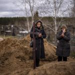 
              Vera Ptitsyna, 63, right, stands with her daughter Olena, 45, as she mourns on her husband's grave, Yuriy Ptitsyn, 74, who died due to lack of medical care during the monthlong Russian occupation of the town, during his funeral in Bucha, in the outskirts of Kyiv, Tuesday, April 19, 2022. (AP Photo/Emilio Morenatti)
            