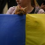 
              A dog peers over a large Ukrainian flag during a protest against Russia's war in Ukraine, in front of the Russian embassy in Bucharest, Romania, Saturday, April 16, 2022. (AP Photo/Andreea Alexandru)
            