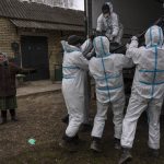 
              Nadiya Trubchaninova, 70, left, stands next to volunteers while loading a plastic bag that contains the body of a civilian killed by Russian soldiers into a truck, in Bucha, in the outskirts of Kyiv, Ukraine, Tuesday, April 12, 2022. (AP Photo/Rodrigo Abd)
            