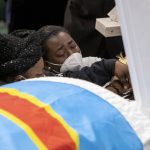 Family and friends cry over the casket with the remains of Patrick Lyoya before the funeral at the Renaissance Church of God in Christ Family Life Center in Grand Rapids, Mich. on Friday, April 22, 2022. The Rev. Al Sharpton demanded that authorities publicly identify the Michigan officer who killed Patrick Lyoya, a Black man and native of Congo who was fatally shot in the back of the head after a struggle, saying at Lyoya's funeral Friday: "We want his name!" (Cory Morse/The Grand Rapids Press via AP)