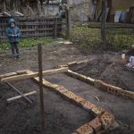 
              In the courtyard of their house, Vlad Tanyuk, 6, looks at the grave of his mother Ira Tanyuk, who died because of starvation and stress due to the war, in Bucha, on the outskirts of Kyiv, Ukraine, Monday, April 4, 2022. Russia is facing a fresh wave of condemnation after evidence emerged of what appeared to be deliberate killings of dozens if not hundreds of civilians in Ukraine. (AP Photo/Rodrigo Abd)
            