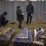 
              CAPTION CORRECTS LOCATION  - Valya Naumenko, 47, identifies the body of her husband Pavlo Ivanyuk, 57, killed by Russian Army, during an exhumation of four civilians killed and buried in a mass grave in Mykulychi, Ukraine on Sunday, April 17, 2022. All four bodies in the village grave were killed on the same street, on the same day. Their temporary caskets were together in a grave. On Sunday, two weeks after the soldiers disappeared, volunteers dug them up one by one to be taken to a morgue for investigation. (AP Photo/Emilio Morenatti)
            