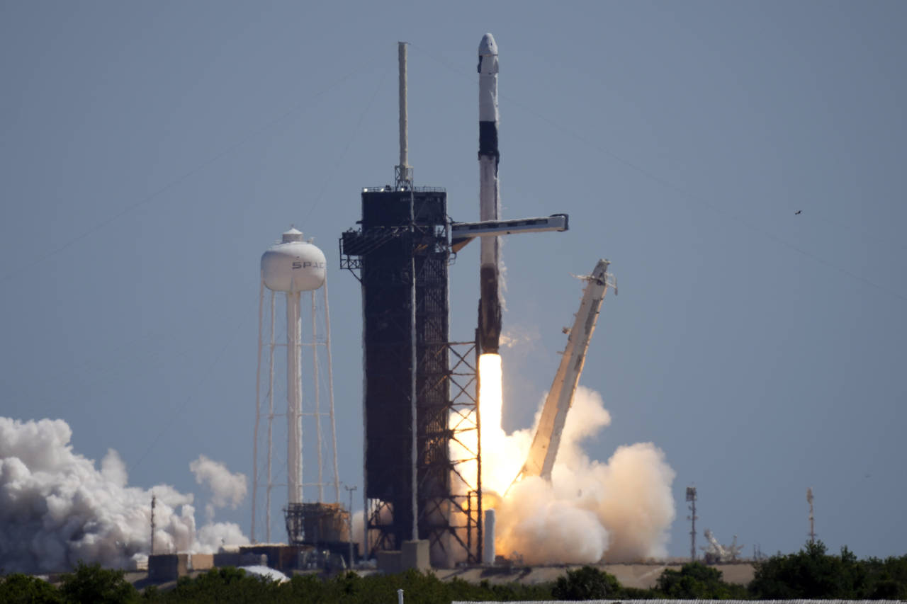 A SpaceX Falcon 9 rocket with the Crew Dragon capsule attached, lifts off with the first private cr...