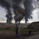 
              A woman walks as smoke rises in the air in the background after shelling in Odesa, Ukraine, Sunday, April 3, 2022. (AP Photo/Petros Giannakouris)
            
