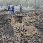 
              Men stands next to a crater of an explosion after night shelling in Kramatorsk, Ukraine, Monday, April 18, 2022. (AP Photo/Andriy Andriyenko)
            