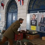 
              A farmer sets up at the Salies de Bearn market, southwestern France, in front of presidential campaign posters of French President and centrist candidate for reelection Emmanuel Macron and French far-right presidential candidate Marine Le Pen, right, Saturday, April 23, 2022. French President Emmanuel Macron is facing off against far-right challenger Marine Le Pen in France's April 24 presidential runoff. (AP Photo/Bob Edme)
            