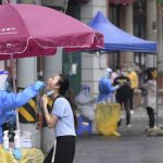 
              In this photo released by Xinhua News Agency, a worker takes a swab sample from a resident for nucleic acid test in Huangpu District in Shanghai, China, on Tuesday, April 26, 2022. (Li He/Xinhua via AP)
            