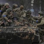 
              Ukrainian servicemen climb on a fighting vehicle outside Kyiv, Ukraine, Saturday, April 2, 2022. As Russian forces pull back from Ukraine's capital region, retreating troops are creating a "catastrophic" situation for civilians by leaving mines around homes, abandoned equipment and "even the bodies of those killed," President Volodymyr Zelenskyy warned Saturday. (AP Photo/Vadim Ghirda)
            