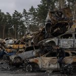 
              A man walks next a storage place for burned vehicles in Irpin, on the outskirts of Kyiv, Thursday, April 21, 2022. (AP Photo/Petros Giannakouris)
            