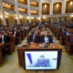 
              Romanian lawmakers listen to Ukraine's President Volodymyr Zelenskyy's speech via video link, on a screen, in Romania's Parliament in Bucharest, Romania, Monday, April 4, 2022. Ukraine's President Volodymyr Zelenskyy addressed Romania's parliament Monday evening in a video call in which the leader labeled the alleged crimes of Russia's forces against Ukrainian civilians in the town of Bucha a "genocide" and called for tougher sanctions against Russia.(AP Photo/Andreea Alexandru)
            