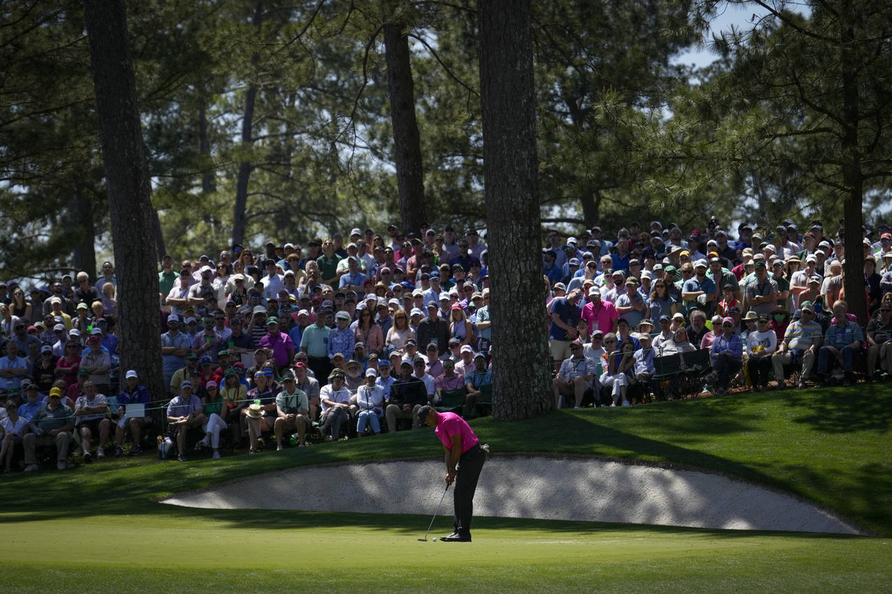 Tiger Woods putts on the 10th green during the first round at the Masters golf tournament on Thursd...