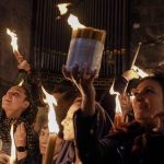 
              Christian pilgrims hold candles as they gather during the ceremony of the Holy Fire at Church of the Holy Sepulchre, where many Christians believe Jesus was crucified, buried and rose from the dead, in the Old City of Jerusalem dead, Saturday, April 23, 2022. (AP Photo/Maya Alleruzzo)
            