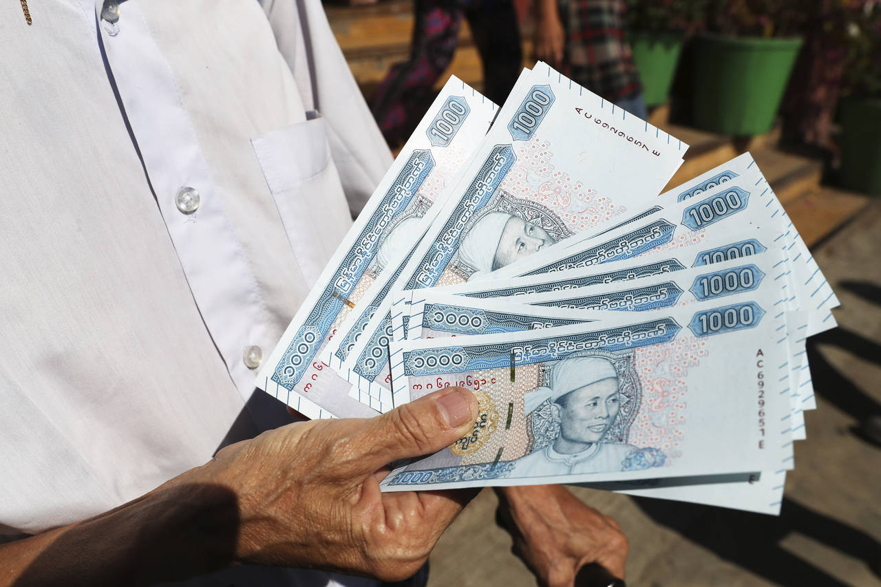 FILE - A man shows new currency notes outside Myanmar Economic Bank Tuesday, Jan. 7, 2020, in Yango...