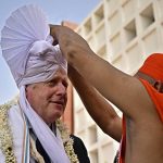 
              Britain's Prime Minister Boris Johnson, left, has a traditional turban tied on his head as he arrives to visit the Gujurat Biotechnology University, in Gandhinagar, part of his two-day trip to India, Thursday, April 21, 2022. (Ben Stansall/Pool Photo via AP)
            
