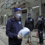 Hong Kong Chief Executive Carrie Lam, left, holds a package of coronavirus prevention materials to be delivered to people during an anti-epidemic event in Hong Kong, Saturday, April 2, 2022. Hong Kong authorities on Saturday asked the entire population of more than 7.4 million people to voluntarily test themselves for COVID-19 at home for three days in a row starting next week. (AP Photo/Kin Cheung)