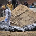 
              Men wearing protective gear exhume the bodies of civilians killed during the Russian occupation in Bucha, in the outskirts of Kyiv, Ukraine, Wednesday, April 13, 2022. Dozens of bodies of civilians executed by the Russian troops have been exhumed already from the mass grave. (AP Photo/Efrem Lukatsky)
            