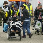 
              Volunteers help a refugee in a wheelchair after fleeing the war from neighboring Ukraine, at the border crossing in Medyka, southeastern Poland, Wednesday, April 6, 2022. (AP Photo/Sergei Grits)
            