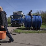 
              Local residents fill cans with water from a water tank installed for residents of Toretsk, eastern Ukraine, Monday, April 25, 2022. Toretsk residents have had no access to water for more than two months because of the war. (AP Photo/Evgeniy Maloletka)
            