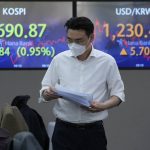 
              A currency trader passes by screens showing the Korea Composite Stock Price Index (KOSPI), left, and the foreign exchange rate between U.S. dollar and South Korean won, at the foreign exchange dealing room of the KEB Hana Bank headquarters in Seoul, South Korea, Friday, April 15, 2022. Asian shares fell in muted trading as markets remained closed for Good Friday and other holidays. (AP Photo/Ahn Young-joon)
            