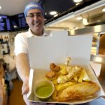 
              Harry Niazi serves a box of 'Platinum Jubilee Feast' a special selection to celebrate Britain's Queen Elizabeth II's Jubilee year, of cod, chips and mushy peas with additional deep fried scampi and prawns, all cooked in sunflower oil at Olleys Fish Experience in Herne Hill in London, Thursday, April 21, 2022. Global cooking oil prices have been rising since the COVID-19 pandemic began and Russia's war in Ukraine has sent costs spiralling. It is the latest fallout to the global food supply from the war, with Ukraine and Russia the world’s top exporters of sunflower oil. And it's another rising cost pinching households and businesses as inflation soars. (AP Photo/Kirsty Wigglesworth)
            