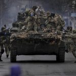
              Ukrainian servicemen climb on a fighting vehicle outside Kyiv, Ukraine, Saturday, April 2, 2022. As Russian forces pull back from Ukraine's capital region, retreating troops are creating a "catastrophic" situation for civilians by leaving mines around homes, abandoned equipment and "even the bodies of those killed," President Volodymyr Zelenskyy warned Saturday. (AP Photo/Vadim Ghirda)
            
