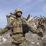 
              A Ukrainian serviceman opens his arms in front of an apartment building damaged by shelling in the city of Chuhuiv, Kharkiv region, Ukraine, Friday, April 8, 2022. (AP Photo/Andrew Marienko)
            