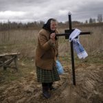 
              Nadiya Trubchaninova, 70, cries while holding the cross of her son Vadym, 48, who was killed by Russian soldiers last March 30 in Bucha, during his funeral in the cemetery of Mykulychi, on the outskirts of Kyiv, Ukraine, Saturday, April 16, 2022. After nine days since the discovery of Vadym's corpse, finally Nadiya could have a proper funeral for him. This is not where Nadiya Trubchaninova thought she would find herself at 70 years of age, hitchhiking daily from her village to the shattered town of Bucha trying to bring her son's body home for burial. (AP Photo/Rodrigo Abd)
            