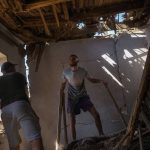 
              Yaroslav Lazarenko, left, and his cousin Alexei remove debris from his destroyed house after a Russian rocket, hit by Ukraine's anti-aircraft system, stroke in a residencial area in Zaporizhzhia, Ukraine, Thursday, April 28, 2022. The strike came as parts of southern Ukraine prepare for a further advance by Russian forces who seek to strip the country of its seacoast. (AP Photo/Francisco Seco)
            