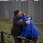 
              Ira Slepchenko, 54, and Valya Naumenko, 47, embrace each other, mourning the death of their respective husbands, during an exhumation of four civilians killed and buried in a mass grave in Mykulychi, Ukraine on Sunday, April 17, 2022. All four bodies in the village grave were killed on the same street, on the same day. Their temporary caskets were together in a grave. On Sunday, two weeks after the soldiers disappeared, volunteers dug them up one by one to be taken to a morgue for investigation. (AP Photo/Emilio Morenatti)
            