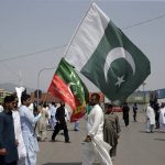 
              Supporter of ruling party Pakistan Tehreek-e-Insaf (PTI) hold the national flag during a protest in Islamabad, Pakistan, Sunday, April 3, 2022. Pakistan's embattled Prime Minister Imran Khan said Sunday he will seek early elections after sidestepping a no-confidence challenge and alleging that a conspiracy to topple his government had failed. (AP Photo/Rahmat Gul)
            