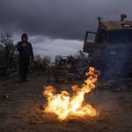 
              A man takes a photo of burning propellant in a street near destroyed Russian military vehicles near Chernihiv, Ukraine, Sunday, April 17, 2022. Witnesses said multiple explosions believed to be caused by missiles struck the western Ukrainian city of Lviv early Monday as the country was bracing for an all-out Russian assault in the east. (AP Photo/Evgeniy Maloletka)
            