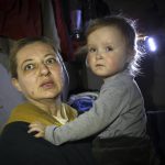 
              A woman holds her child as she speaks to a photographer in the basement of a building damaged during a fighting used as a bomb shelter in Mariupol, on the territory which is now under the Government of the Donetsk People's Republic control, eastern in Mariupol, Ukraine, Friday, April 8, 2022. (AP Photo/Alexei Alexandrov)
            