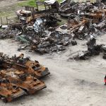 
              People walk past wrecks of military vehicles in Bucha, on the outskirts of Kyiv, Ukraine, Saturday, April 30, 2022. (AP Photo/Emilio Morenatti)
            