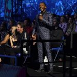 Host Anthony Mackie speaks at the CMT Music Awards on Monday, April 11, 2022, at the Municipal Auditorium in Nashville, Tenn. Laura Savoie and Dennis Quaid, from left, appear in the audience. (AP Photo/Mark Humphrey)
