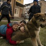 
              Children play with a dog in Bucha, on the outskirts of Kyiv, Ukraine, Friday, April 8, 2022. (AP Photo/Rodrigo Abd)
            