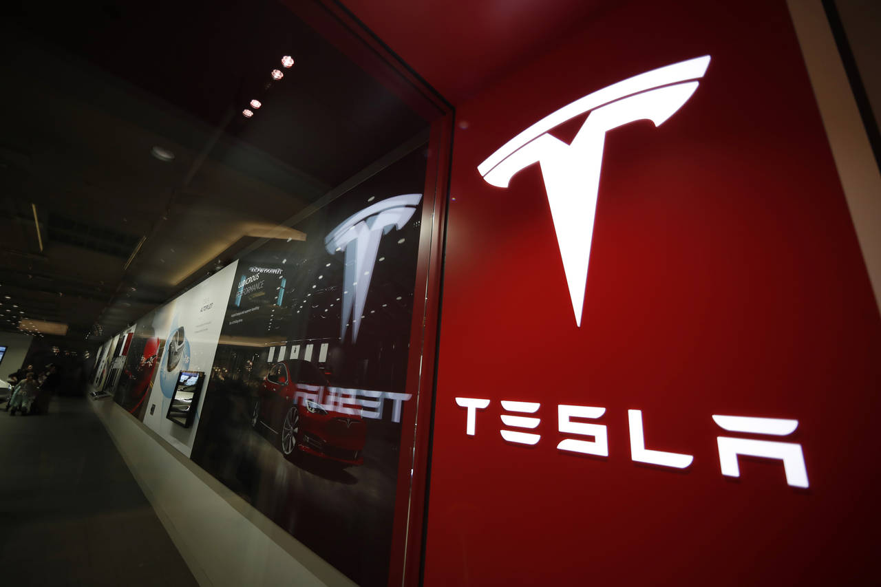 FILE - A sign bearing the company logo outside a Tesla store in Cherry Creek Mall in Denver, Feb. 9...