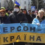 
              People hold a Ukrainian flag with a sign that reads: "Kherson is Ukraine", during a rally against the Russian occupation in Kherson, Ukraine, Sunday, March 20, 2022. Ever since Russian forces took the southern Ukrainian city of Kherson in early March, residents sensed the occupiers had a special plan for their town. Now, amid a crescendo of warnings from Ukraine that Russia plans to stage a sham referendum to transform the territory into a pro-Moscow "people's republic," it appears locals guessed right. (AP Photo/Olexandr Chornyi)
            