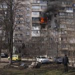 
              FILE - People look at a burning apartment building in a yard after shelling in Mariupol, Ukraine, Sunday, March 13, 2022. (AP Photo/Evgeniy Maloletka, File)
            