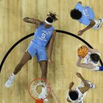 
              North Carolina forward Armando Bacot (5) falls to the court as Kansas guard Christian Braun (2) holds the ball during the first half of a college basketball game in the finals of the Men's Final Four NCAA tournament, Monday, April 4, 2022, in New Orleans. (AP Photo/Brynn Anderson)
            