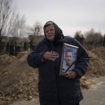 
              A woman carries the portrait of Dmytro Stefienko, 32, a civilian killed during the war with Russia, during his funeral in Bucha, in the outskirts of Kyiv, Ukraine, Tuesday, April 12, 2022. (AP Photo/Rodrigo Abd)
            