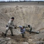
              Interior ministry sappers collect explosives in a hole to detonate them near a mine field after recent battles at the village of Moshchun close to Kyiv, Ukraine, Tuesday, April 19, 2022. (AP Photo/Efrem Lukatsky)
            