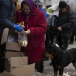 
              People receive food from a church in the town of Borodyanka, about 40 miles northwest of Kyiv, Ukraine, on Sunday, April 10, 2022. Several apartment buildings were destroyed during fighting between the Russian troops and the Ukrainian forces and the town is without electricity, water and heating. (AP Photo/Petros Giannakouris)
            