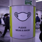 People wearing face masks pass by a poster reminding precautions against the coronavirus at a subway station in Seoul, South Korea, Friday, April 29, 2022. (AP Photo/Ahn Young-joon)